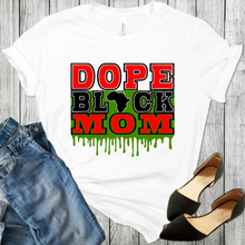 Load image into Gallery viewer, African American T-Shirt Dope Black Mom white t shirt with the words Dope & Mom In red and the word Black in black and the continent Africa replaced the letter A in the word black and green drip behind the words Black & Mom. Also a pair of black shoes and blue jeans in the picture.
