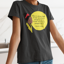 Load image into Gallery viewer, Amanda Gordan bust with red hair ban and gold earing yellow collar with the words There is always light, if inly we're brave enough to see it, If only we're brave enough to be it. Amanda Gorman on a young black woman with a black t-shirt and blue jeans in the kitchen.
